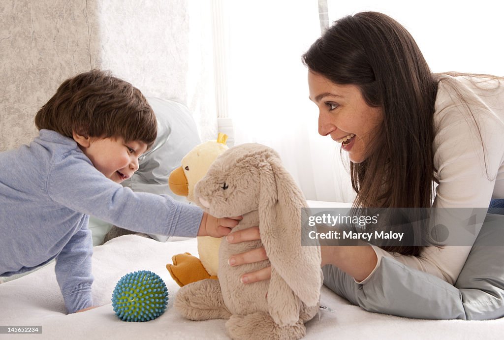 Mom and toddler boy playing with stuffed animals.