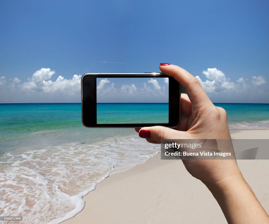 Woman photographing a beach with i-phone