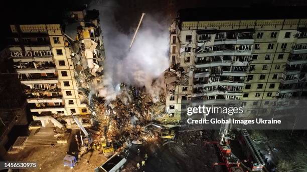 An aerial view of firefighters conducting search and rescue operations at residential building hit by a missile on January 15, 2023 in Dnipro,...