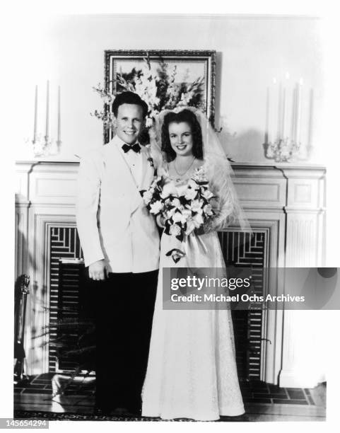 James Dougherty and Marilyn Monroe on their wedding day in Los Angeles being photographed in front of a fireplace 1942.