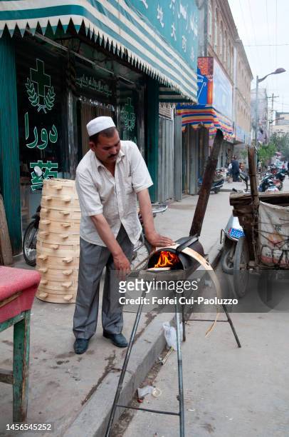 an uyghur man working on a wood craft on the fire at kashgar - ouïgour photos et images de collection