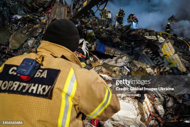 Rescuer stands in front of destroyed residential building while his colleagues conduct search and rescue operations on January 14, 2023 in Dnipro,...