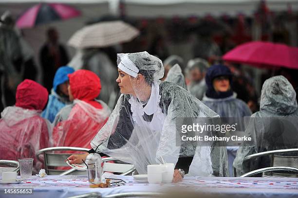 Waitress in a poncho cleans tables at the Kings road street party on June 3, 2012 in London, England. For only the second time in its history the UK...