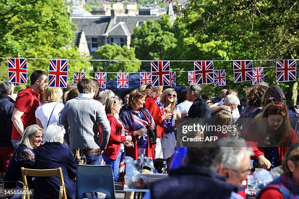 Revellers sit under decorations with Britain's Union flags during a street party to celebrate the Queen's Diamond Jubilee in Edinburgh on June 3,...