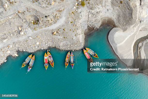 aerial drone view of attabad lake in a beautiful autumn season with traditional fishing boat ,passu , karakoram mountains range in pakistan, asia - asia village river stock pictures, royalty-free photos & images