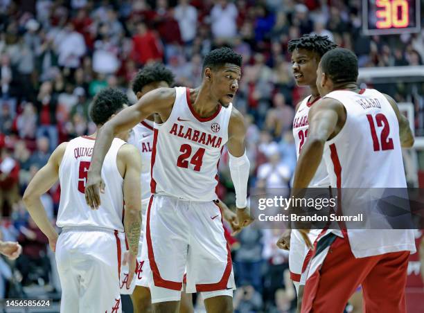 Brandon Miller of the Alabama Crimson Tide is congratulated by teammates Nick Pringle and Delaney Heard after knocking down a first period three...