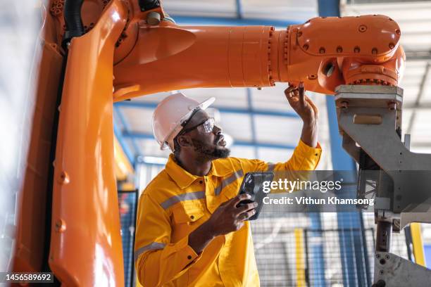 african engineer with tablet inspection the robotic arm and working at manufacturing process - robotica foto e immagini stock