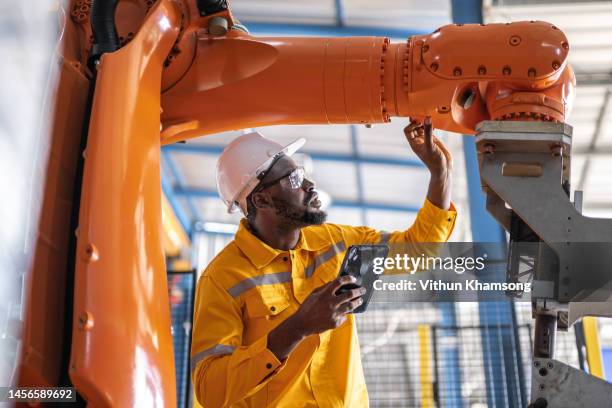 african engineer with tablet inspection the robotic arm and working at manufacturing process - manufacturing equipment stock pictures, royalty-free photos & images