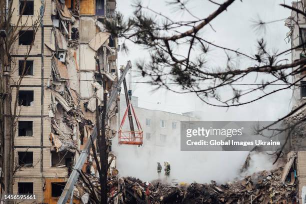 Firefighters are conducting search and rescue operations at residential building hit by missile on January 15, 2023 in Dnipro, Ukraine. Part of the...