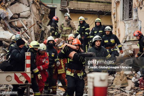 Fireman and rescuers carry a girl rescued from under the rubble on January 15, 2023 in Dnipro, Ukraine. Part of the building was completely destroyed...