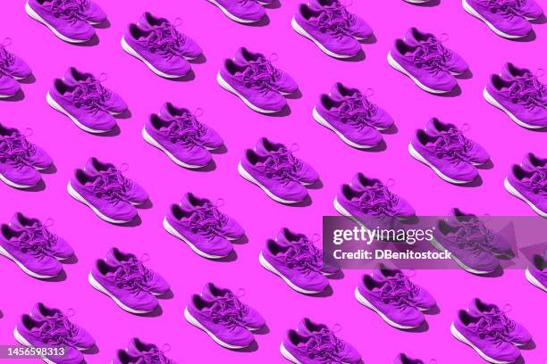 pattern of used purple sneakers on a purple background. concept of exercise, women's day, feminism, marathon, race, healthy life, training and comfort. - purple shoe stock pictures, royalty-free photos & images