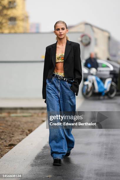 Caroline Daur wears a pale yellow with orange / blue print pattern shoulder-off / cropped top from Etro, a black blazer jacket, a black shiny leather...