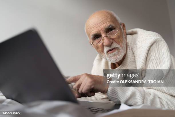 elderly man studing or working at home with laptop - lesebrille stock-fotos und bilder