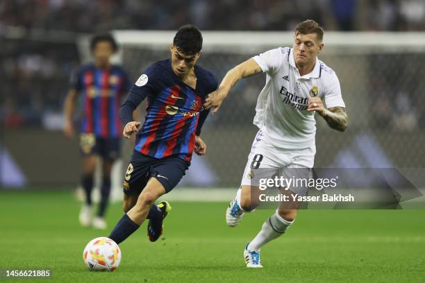 Pedri of FC Barcelona is challenged by Toni Kroos of Real Madrid during the Super Copa de Espana Final match between Real Madrid and FC Barcelona at...