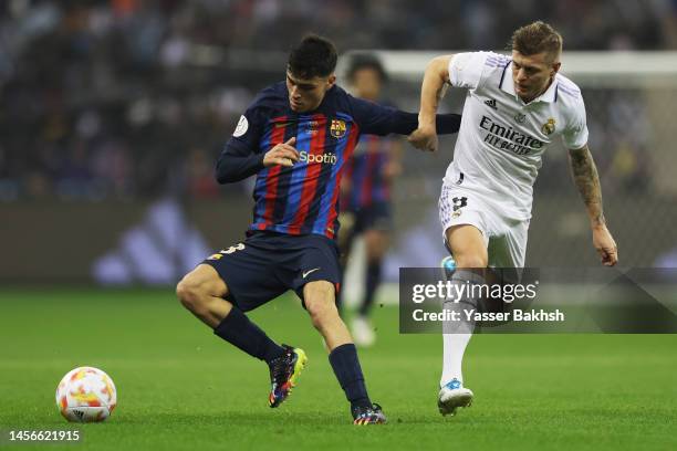 Pedri of FC Barcelona is challenged by Toni Kroos of Real Madrid during the Super Copa de Espana Final match between Real Madrid and FC Barcelona at...