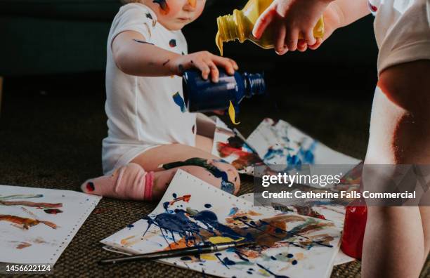 twin girls create a huge mess with primary coloured paints - body art painting fotografías e imágenes de stock