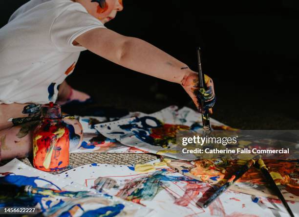 a toddler girl creates a huge mess with primary coloured paints - kids mess carpet fotografías e imágenes de stock