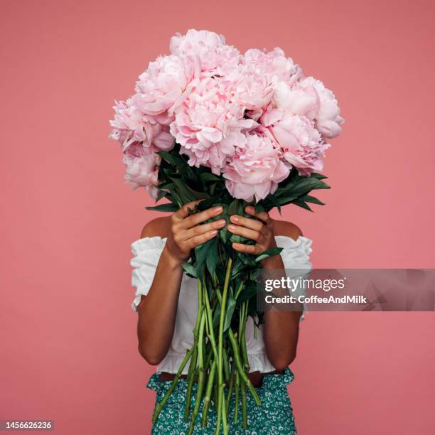 belle femme émotionnelle tenant un bouquet de fleurs - femmes rose photos et images de collection