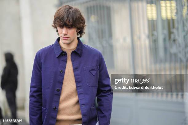 Guest wears a brown wool pullover, a navy blue jacket from Prada, outside Prada, during the Milan Menswear Fall/Winter 2023/2024 on January 15, 2023...