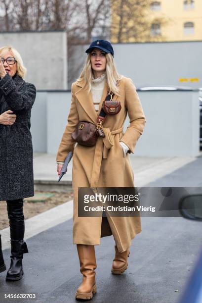 Guest wears Ralph Lauren cap, beige belted coat, Etro bag with micro bag, brown boots outside Etro during the Milan Menswear Fall/Winter 2023/2024 on...