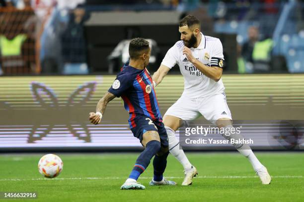 Karim Benzema of Real Madrid is challenged by Raphinha of FC Barcelona during the Super Copa de Espana Final match between Real Madrid and FC...