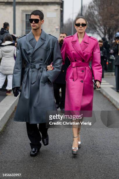 Guest wears black sunglasses, grey belted coat, black pants and a guest wears pink belted coat, black sunglasses, silver platform heels outside Prada...