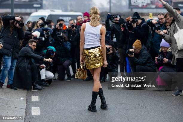 Caroline Caro Daur in front of photographers wears white top with logo, golden skirt, bag, black laced boots outside Prada during the Milan Menswear...
