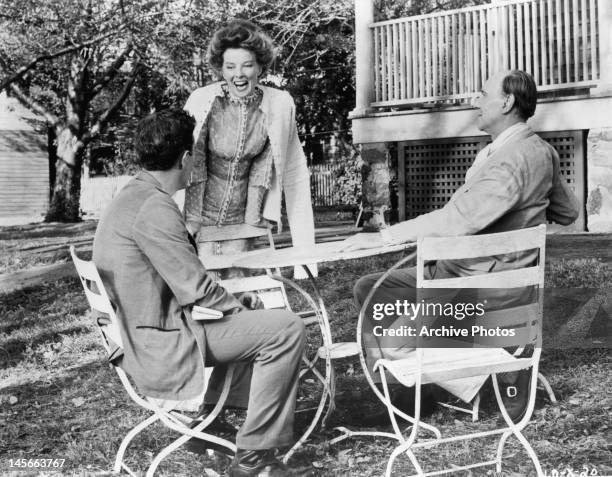 Katharine Hepburn leaning on chair as she talks to man and Ralph Richardson in a scene from the film 'Long Day's Journey Into Night', 1962.