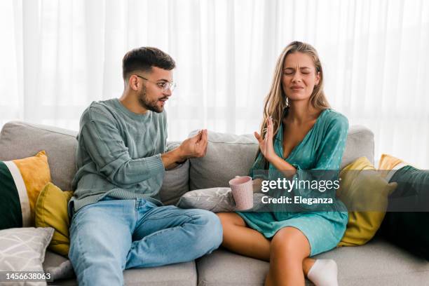 foto de una pareja joven teniendo una discusión en casa - pelea fotografías e imágenes de stock