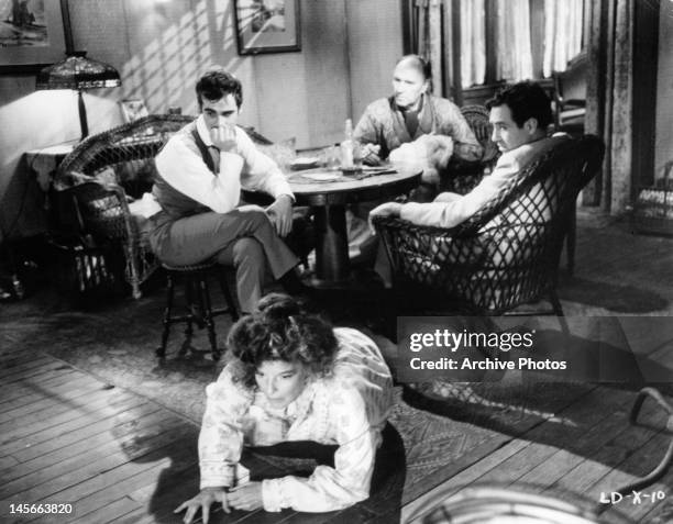 Dean Stockwell, Ralph Richardson, and Jason Robards around the table while Katharine Hepburn is on the ground in a scene from the film 'Long Day's...