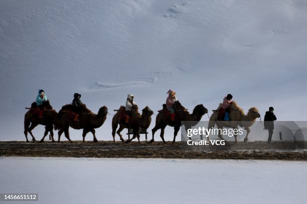 Tourists ride camels at the Mingsha Mountain and Crescent Spring scenic spot after a snowfall on January 14, 2023 in Dunhuang, Jiuquan City, Gansu...