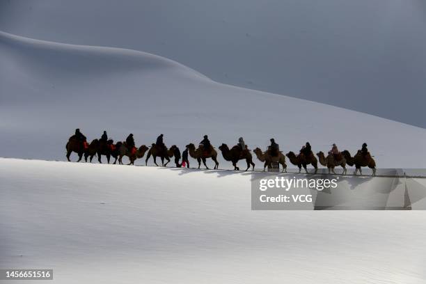 Tourists ride camels at the Mingsha Mountain and Crescent Spring scenic spot after a snowfall on January 14, 2023 in Dunhuang, Jiuquan City, Gansu...