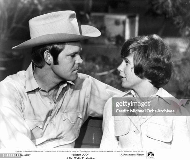 Glen Campbell and Kim Darby sitting on a bench looking into one anothers eyes in a scene from the film 'Norwood', 1969.