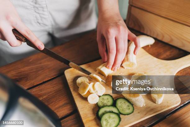 close up photo of woman hands making a healthy detox drink in a blender - a green smoothie with bananas, green spinach and avocado. healthy eating concept, ingredients for smoothies on the table. - ent stockfoto's en -beelden