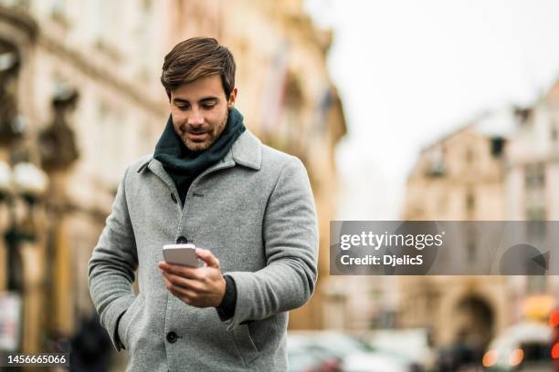 happy young man using phone on the street. - s happy days stock pictures, royalty-free photos & images