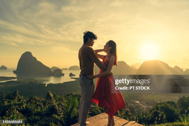 man and woman in red dress standing in hug like dancing in view of ao samet nang chee phang nga with sea and mountains in phang nga province, thailand - red sea rain stock pictures, royalty-free photos & images