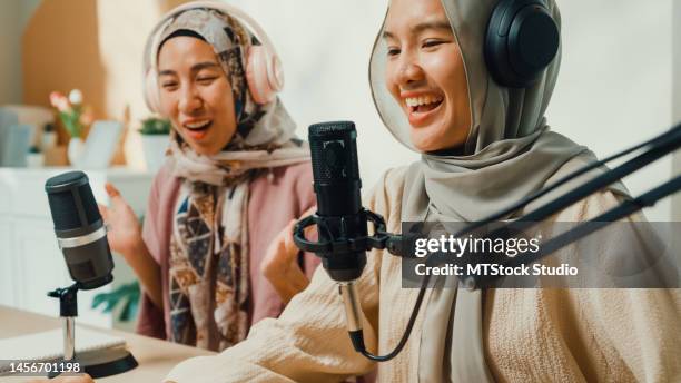 happy muslim asian girl friends wear hijab and headphone record podcast on laptop talk microphone onair live stream with audience and guest at living room. - live evenemang bildbanksfoton och bilder