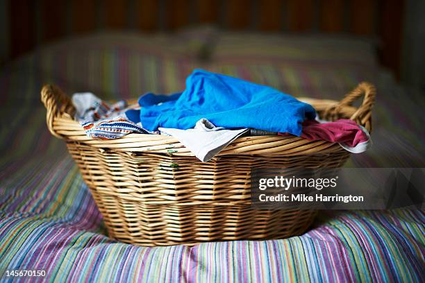 filled laundry basket on bed - laundry basket foto e immagini stock