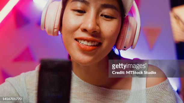 close-up microphone happy asian musician girl influencer wear headphone play guitar voice record podcast online live stream sing song at studio neon light. - booth stock pictures, royalty-free photos & images