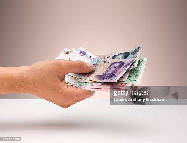 hand holding chinese yuan currency - chinese currency stock pictures, royalty-free photos & images