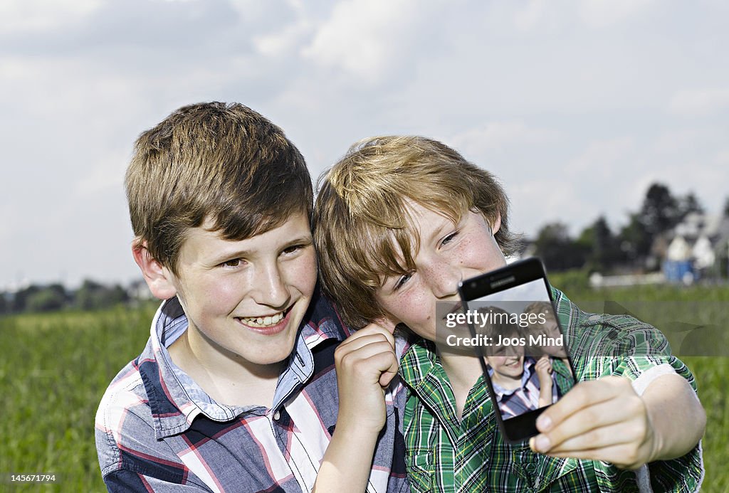 Boys using smart phone outdoors, self photo