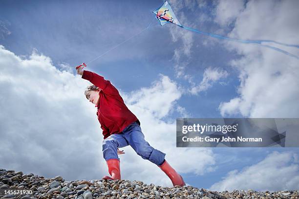 young boy flying kite on pebble  beach - aldeburgh stock pictures, royalty-free photos & images