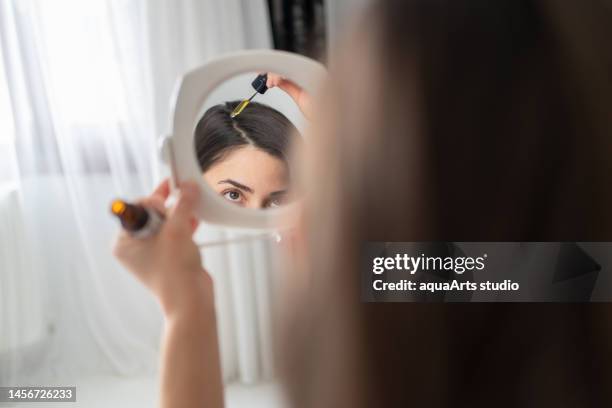 portrait of applying hair serum to her hair - 血清樣本 個照片及圖片檔