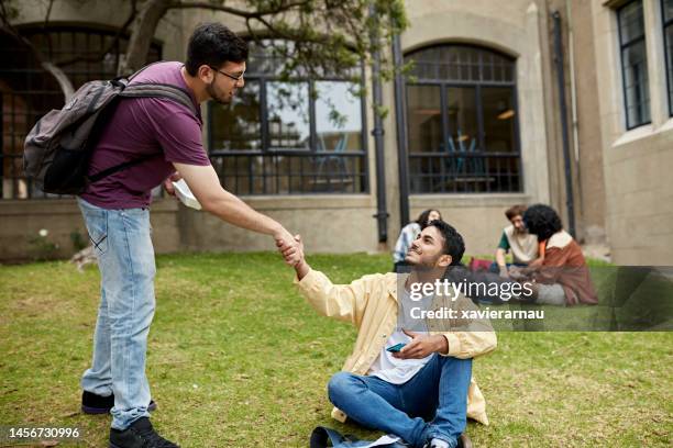 young male university students shaking hands - sitting on floor stock pictures, royalty-free photos & images