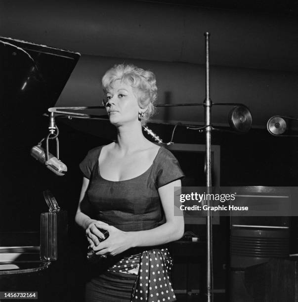 Belgian-American actress and dancer Monique van Vooren , wearing a cap sleeve dress with a scooped neckline, and a polka dot sash belt, in an...