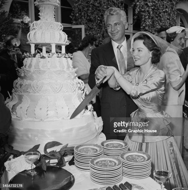 American actress Wanda Hendrix and her husband, American businessman and powerboat racer Jim Stack , cutting their wedding cake at the reception...