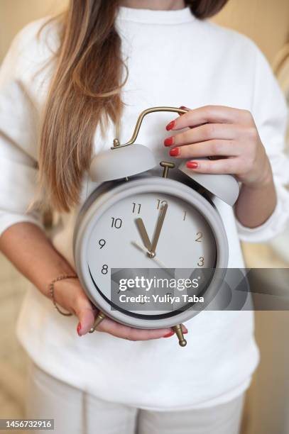 mittelteil einer frau, die eine runde uhr in den händen hält. - biologische uhr stock-fotos und bilder