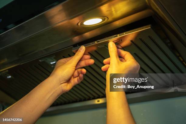 cropped shot of woman hands trying to removing a filters from cooker hood for cleaning it. - filtered foto e immagini stock