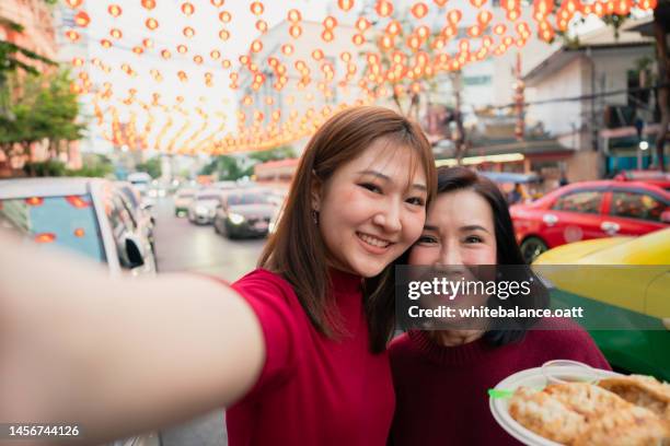 asian mother and daughter traveling and eating street food at chinatown on chinese new year. - family looking at camera stock pictures, royalty-free photos & images