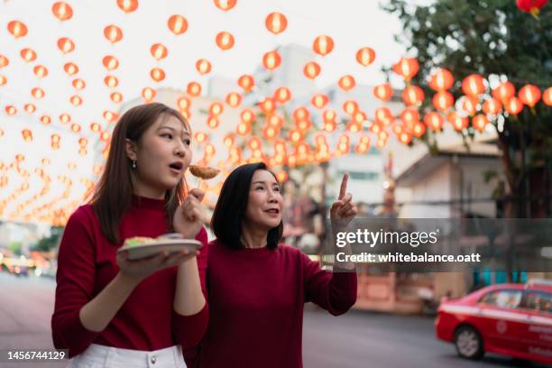 madre e hija asiáticas viajan y comen comida callejera en chinatown en el año nuevo chino. - 20 year woman looking no smile casual setting fotografías e imágenes de stock